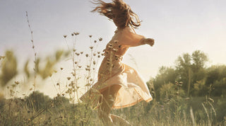 Frau in Kleid springt in Feld