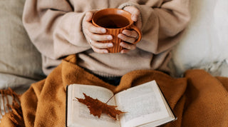 Frau ließt mit Tee in der Hand im Herbst