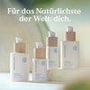 Die Hyaluron-Nachtcreme von Nature Love in einer weißen Flasche mit einer Holzpumpe wird auf einer hellen Fläche präsentiert. Der deutsche Text darüber lautet: "Für das Natürlichste der Welt: dich.